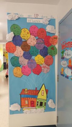 a bulletin board with balloons attached to the door and welcome home sign on the wall