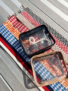 two pieces of luggage sitting on top of a picnic table next to sunglasses and bracelets