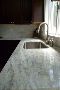 a kitchen with marble counter tops and dark wood cabinetry is pictured in this image