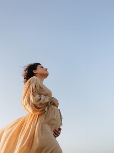 a woman in a long dress looking up into the sky