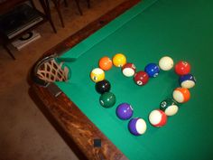 pool balls arranged in the shape of a heart on a green billiards table