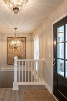 an entry way with a chandelier and wooden door leading to the second floor