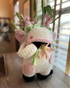 a crocheted stuffed animal with flowers in it's mouth sitting on a table