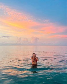 a woman sitting in the water at sunset