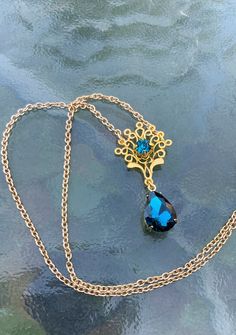 This is one of the beautiful necklaces that Kate wears in Bridgerton 2. It reminds me of a peacock with the shape and teal blue colors. It is made with a gold tone filigree that has a teal blue rhinestone set into the center. Another teal blue drop rhinestone hangs from the bottom. Choose your preferred length, as shown it is 16 inches. This lovely piece makes a great gift for a loved one or yourself. Elegant Gold Necklace With Peacock Design, Elegant Blue Peacock Design Jewelry, Elegant Peacock Design Necklace For Gift, Victorian Turquoise Necklace For Wedding, Blue Filigree Necklace For Wedding, Elegant Peacock Color Pendant Jewelry, Formal Gold Necklace With Peacock Design, Vintage Jewelry With Peacock Design As Gift, Vintage Jewelry With Peacock Design For Gift