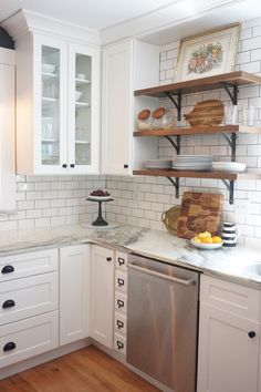 a kitchen with white cabinets and wood flooring on the counter top, along with open shelving