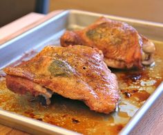 two pieces of meat sitting on top of a pan covered in sauce and seasoning