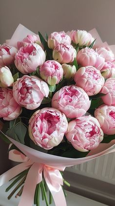 a bouquet of pink and white tulips in a vase with ribbon on the side