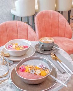 a table topped with two bowls of food next to cups and saucers on top of it