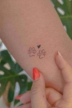 a woman's arm with two paw prints and a heart tattoo on the wrist