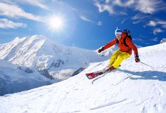 a man riding skis down the side of a snow covered slope on a sunny day