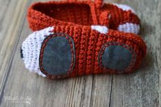 an orange and white crocheted baby booties with black buttons on the side