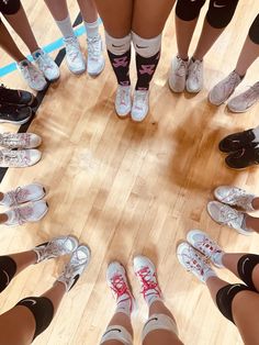 a group of people standing in a circle on top of a hard wood floor with their feet up