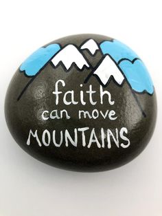 a rock with the words faith can move mountains painted on it, sitting in front of a white background