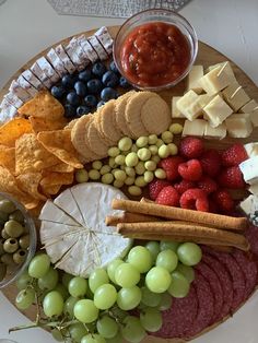 a platter filled with cheese, crackers, grapes, and other food items