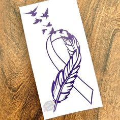 a piece of paper with a drawing of a feather and butterflies on it, sitting on top of a wooden table