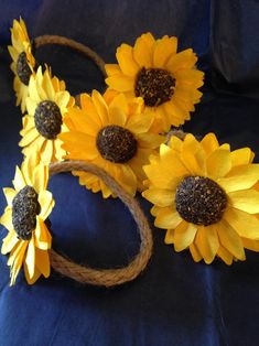 three sunflowers are tied to rope and placed on a blue cloth with twine