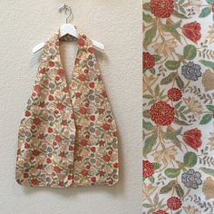 two pieces of cloth hanging on a wall next to a flowered curtain with white hangers