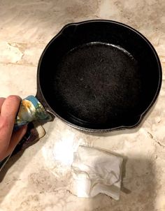 a person is holding an empty cast iron skillet