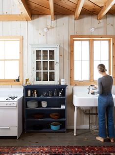 a woman standing in a kitchen next to a sink