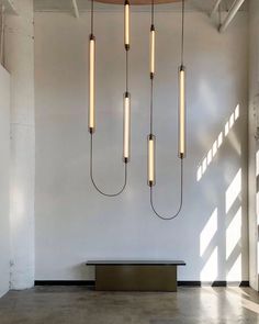 a room with some lights hanging from the ceiling and a bench in front of it