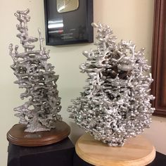 two silver vases sitting next to each other on top of a wooden stand in front of a mirror