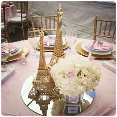 the table is set with plates, silverware and pink napkins in front of the eiffel tower