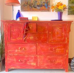 an orange painted dresser with flowers on top