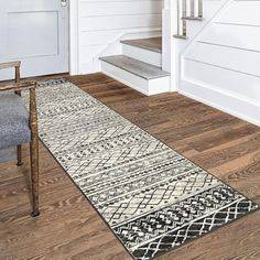 a white and black runner rug in front of a door with stairs leading up to it