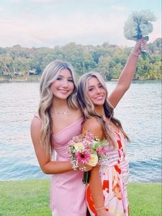 two beautiful young women standing next to each other in front of a body of water