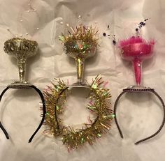 three different types of hair accessories on a white sheet with pink and gold decorations around them