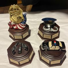 four police trophies are sitting on top of a white tablecloth covered table with an american flag