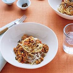 two white bowls filled with food next to silverware and spoons on a table