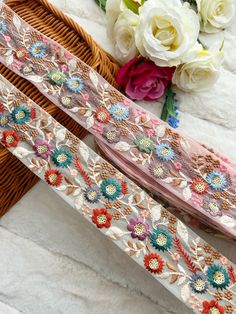 two ribbons with flowers on them sitting next to each other in front of a basket