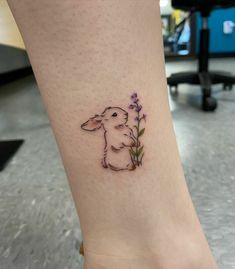 a small tattoo of a rabbit holding a flower in it's right leg, on the ankle