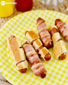 four hot dogs wrapped in bacon on a yellow and white plate