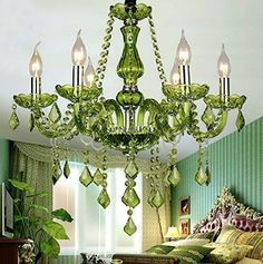 a green chandelier hanging over a bed in a room with curtains and pillows