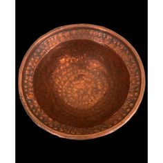 a copper colored bowl on a black background