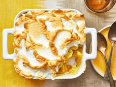 a casserole dish on a yellow table with spoons