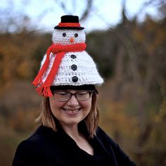 a woman wearing a crocheted snowman hat with red and white pom - pom