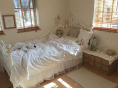 a white bed sitting in a bedroom next to two windows