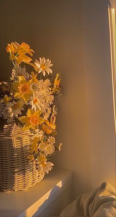 a basket filled with yellow and white flowers sitting on top of a window sill