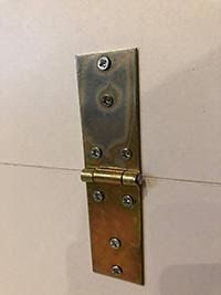 an image of a metal door handle on a white wall with screws in it