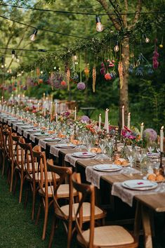 a long table is set with candles, plates and place settings for an outdoor dinner