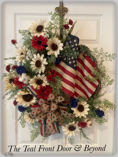 a patriotic wreath with flowers and an american flag hanging on the front door for memorial day