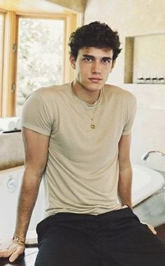 a young man sitting on top of a table next to a sink in a bathroom