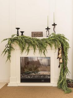 a fireplace decorated with evergreen and candles