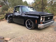 an old black truck is parked in the dirt