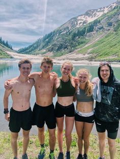 a group of people standing next to each other in front of a body of water