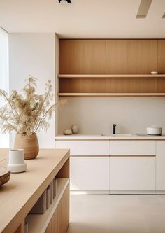 a vase with some flowers in it sitting on a counter next to a sink and cabinets